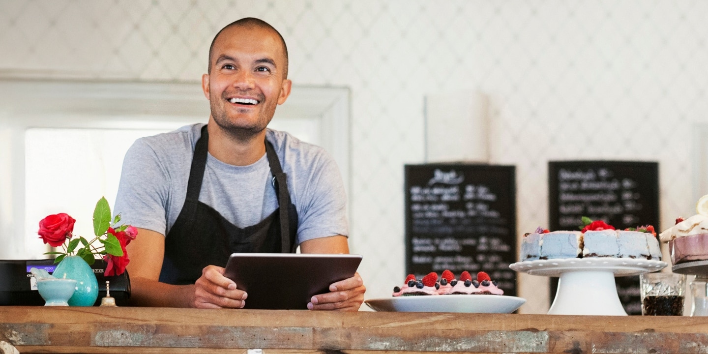 A man at a bakery using a tablet.  