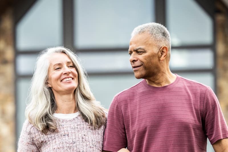 A couple walking together outdoors, smiling at each other.