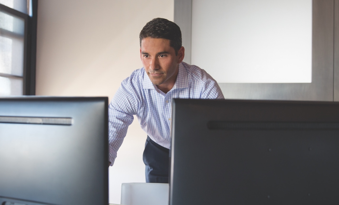 An investor stands near his computer