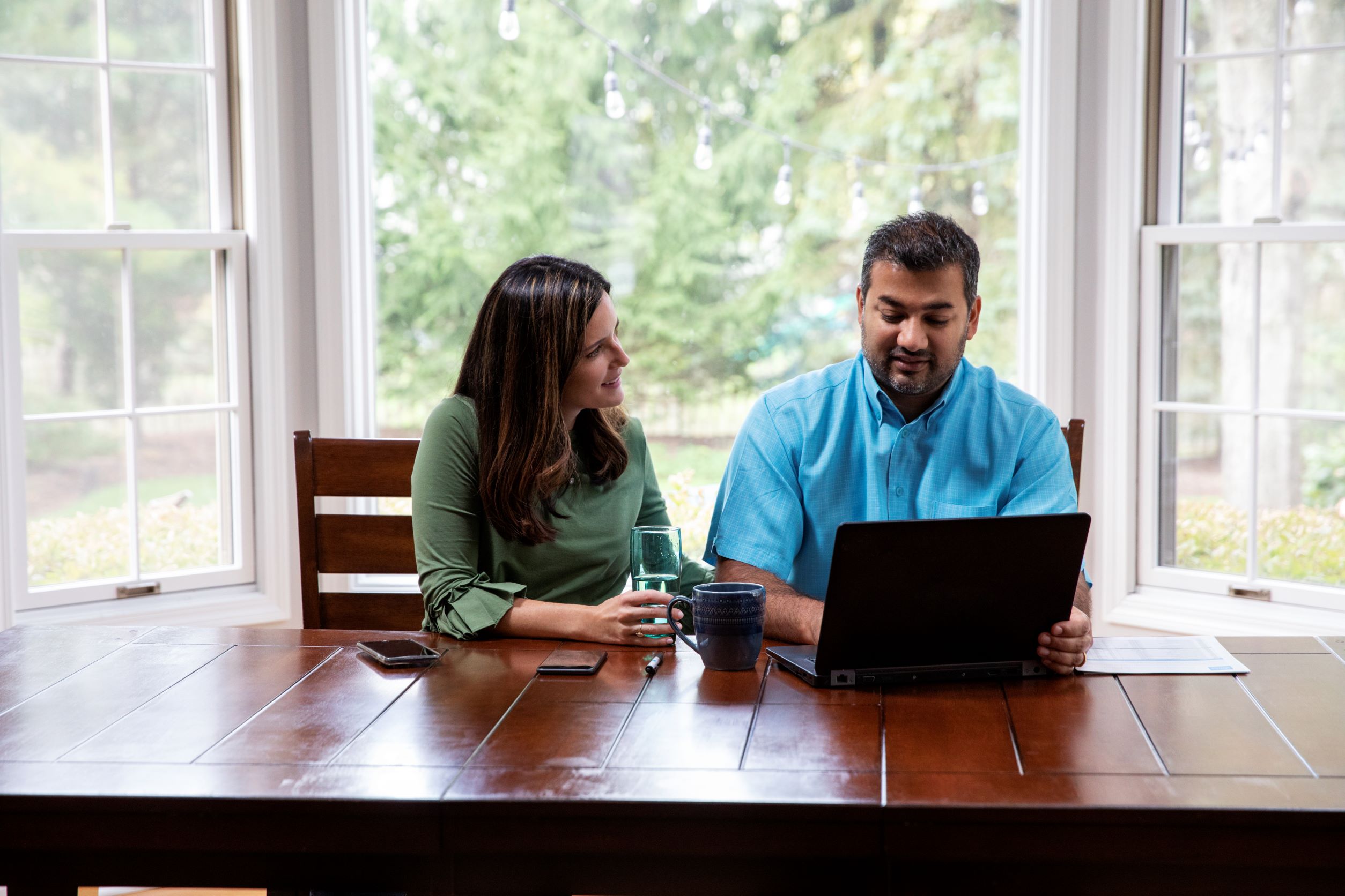 Couple sitting at a table with their laptop