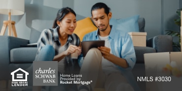 A couple looks at a tablet together in their living room.