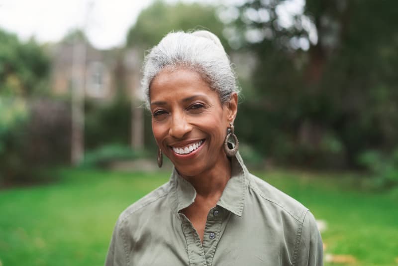 Rose, a woman in her 60s, smiles while standing outdoors.